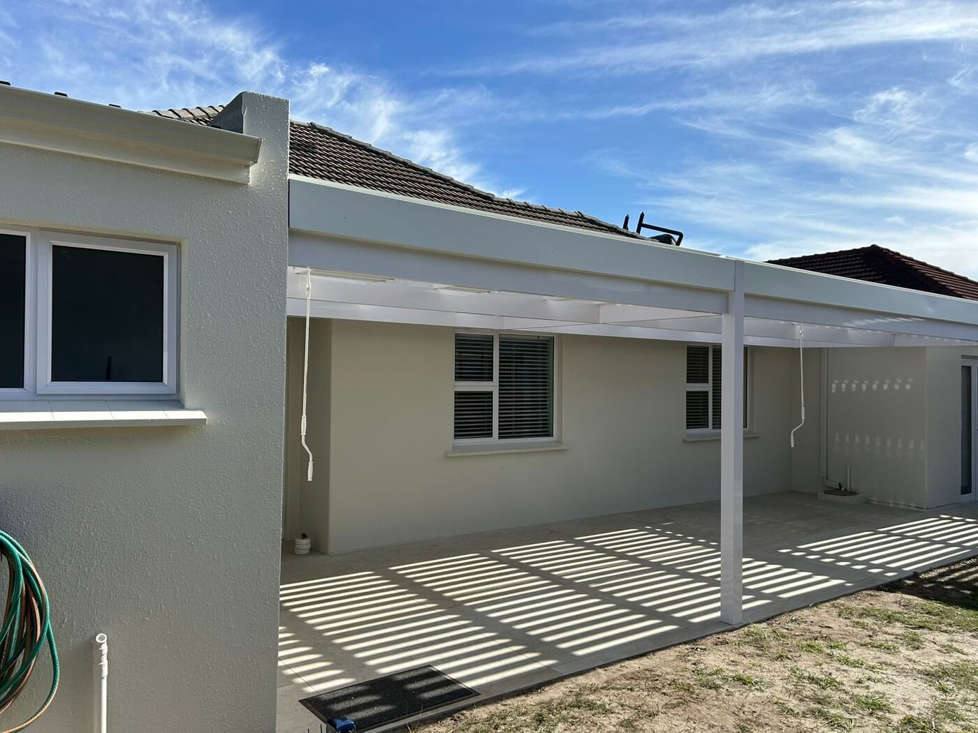 Full-white aluminium louvre awning with white frame and blades over a paved patio at a home in Bellville, Cape Town.