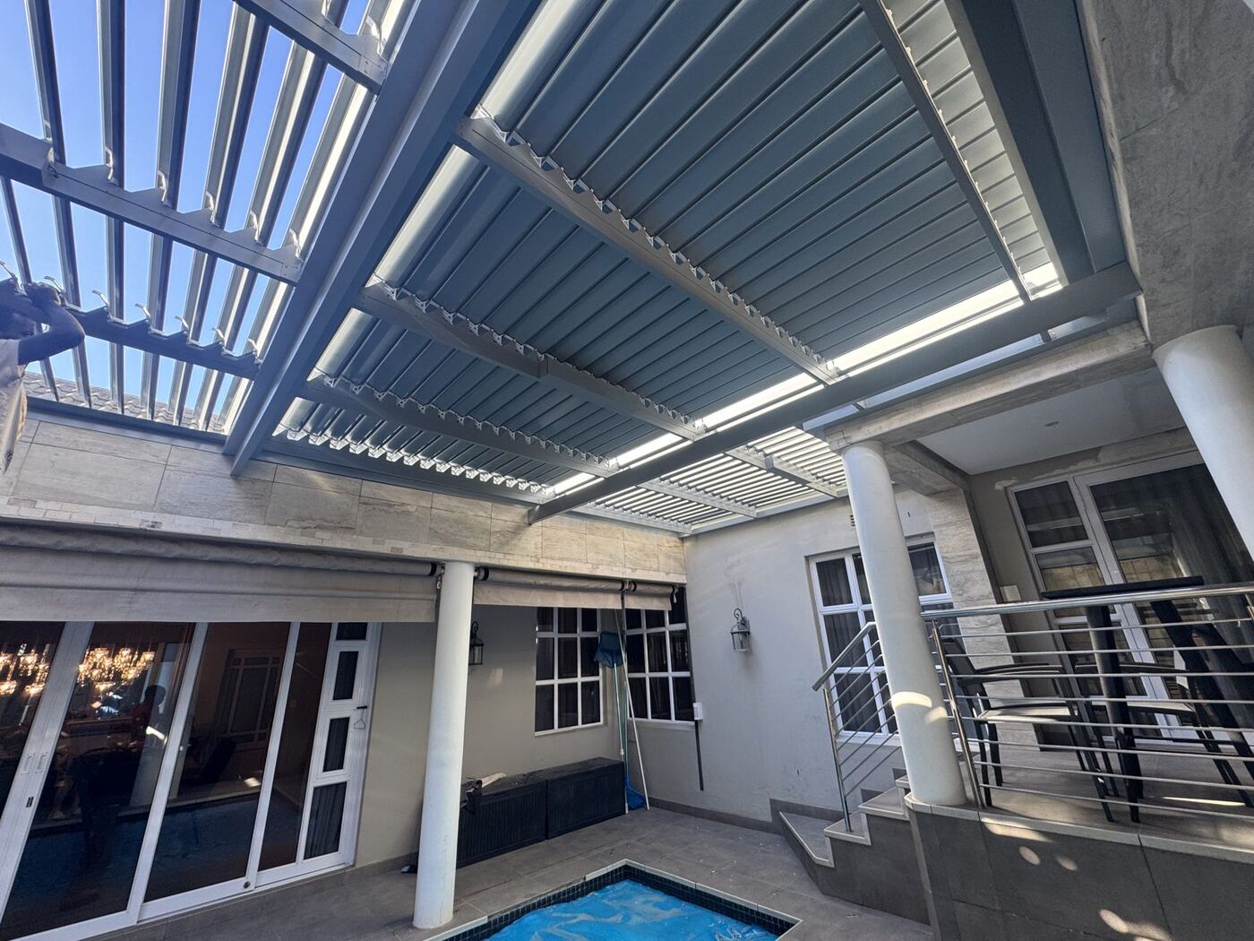 Light grey frame & blades aluminium louvre roof over a patio in Goedemoed, Cape Town.
