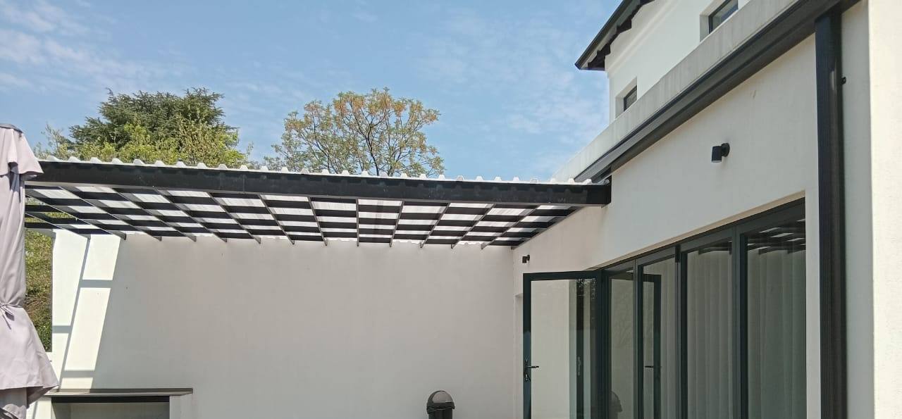 Clear polycarbonate roof on a black aluminium frame over a courtyard