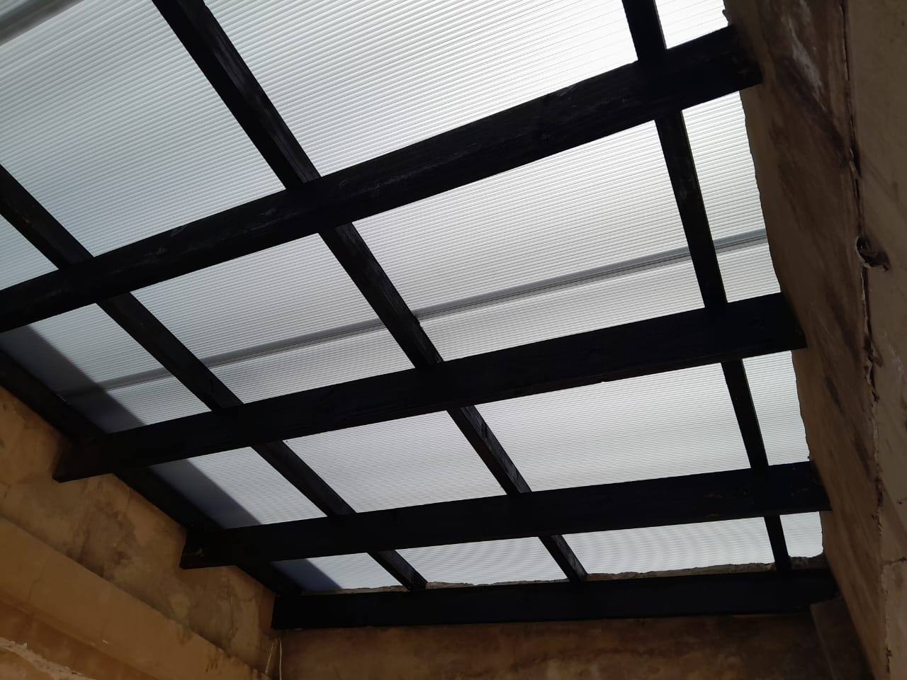 Underside of opal multiwall polycarbonate panels on black rafters